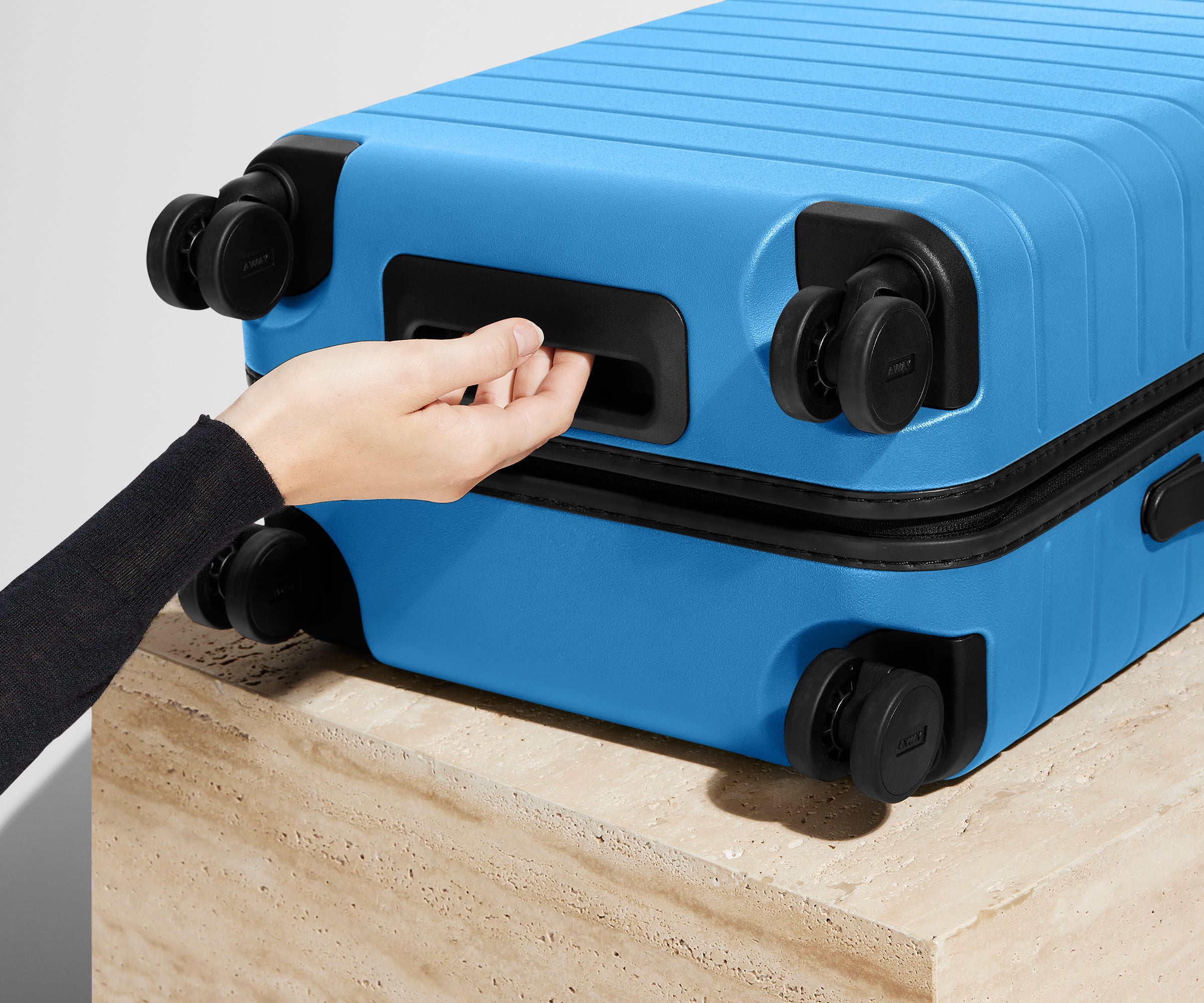The Bigger Carry-On suitcase in Splash Blue shown from below highlighting the underside grab handle