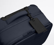 The Softside Compact Carry-On suitcase in Navy Blue shown shown from above highlighting the recycled leather luggage tag