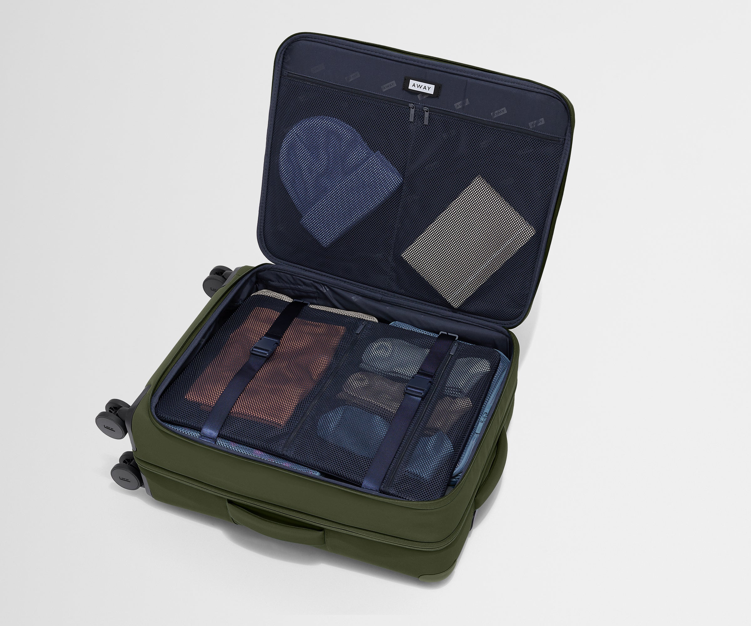 The Softside Medium suitcase in Olive Green shown open on its side and packed with Away's packing organizers to show capacity and the interior compression system, designed to help you pack more in