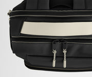 Close-up of a black backpack with beige stitching on a light gray background