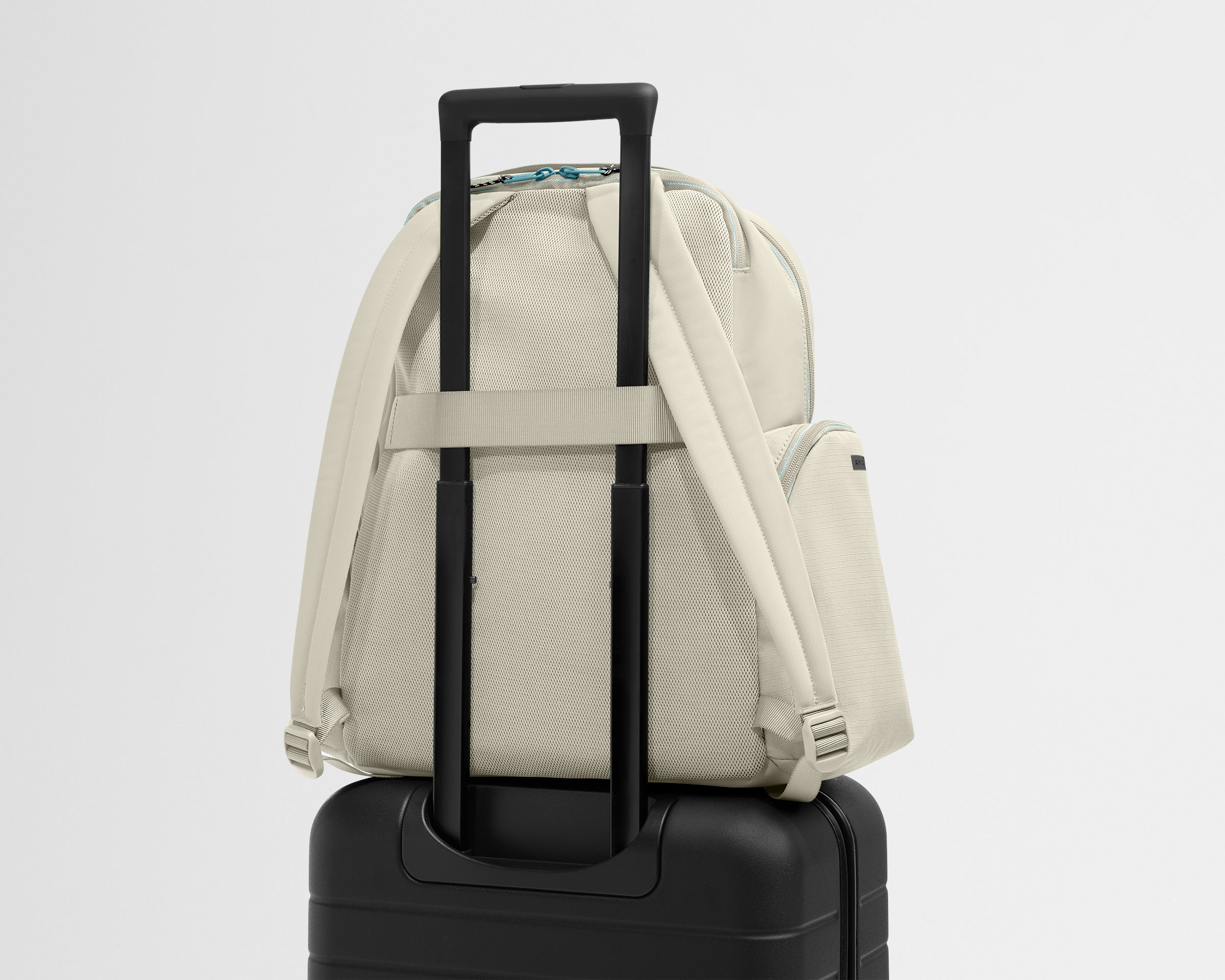 Beige backpack with a black suitcase on a gray background