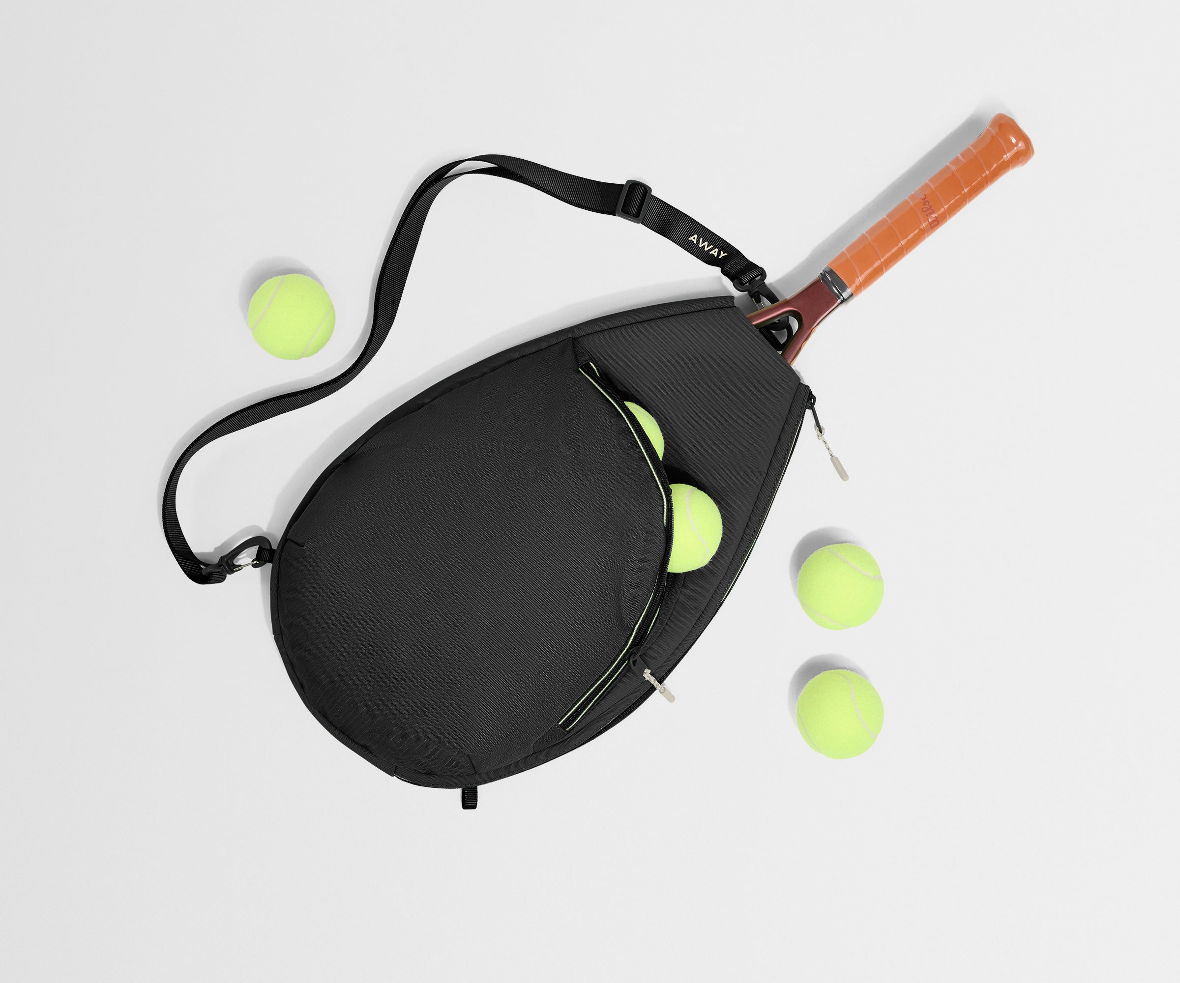 Tennis racket with black case and multiple tennis balls on a light gray background