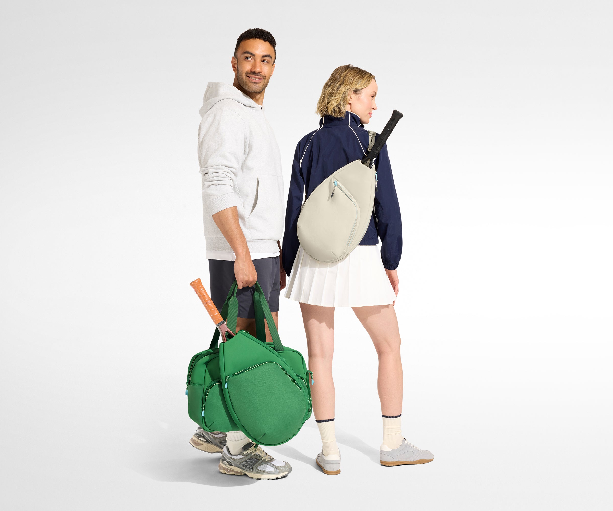Two people with tennis bags and rackets on a white background