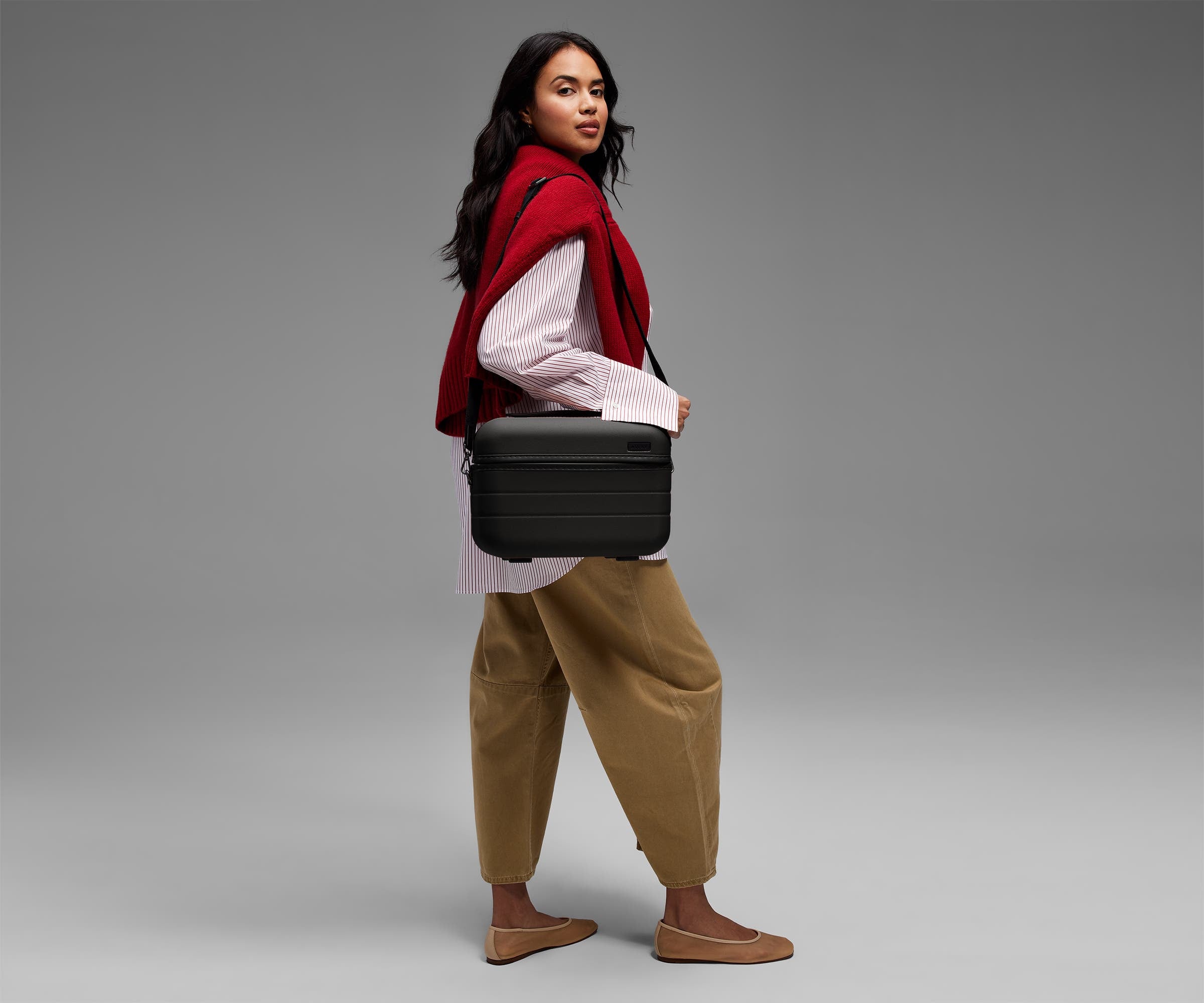 Person wearing the Train Case on their shoulder using the detachable shoulder strap