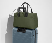 The Overnight Bag secured to an Away checked suitcase using the trolley sleeve