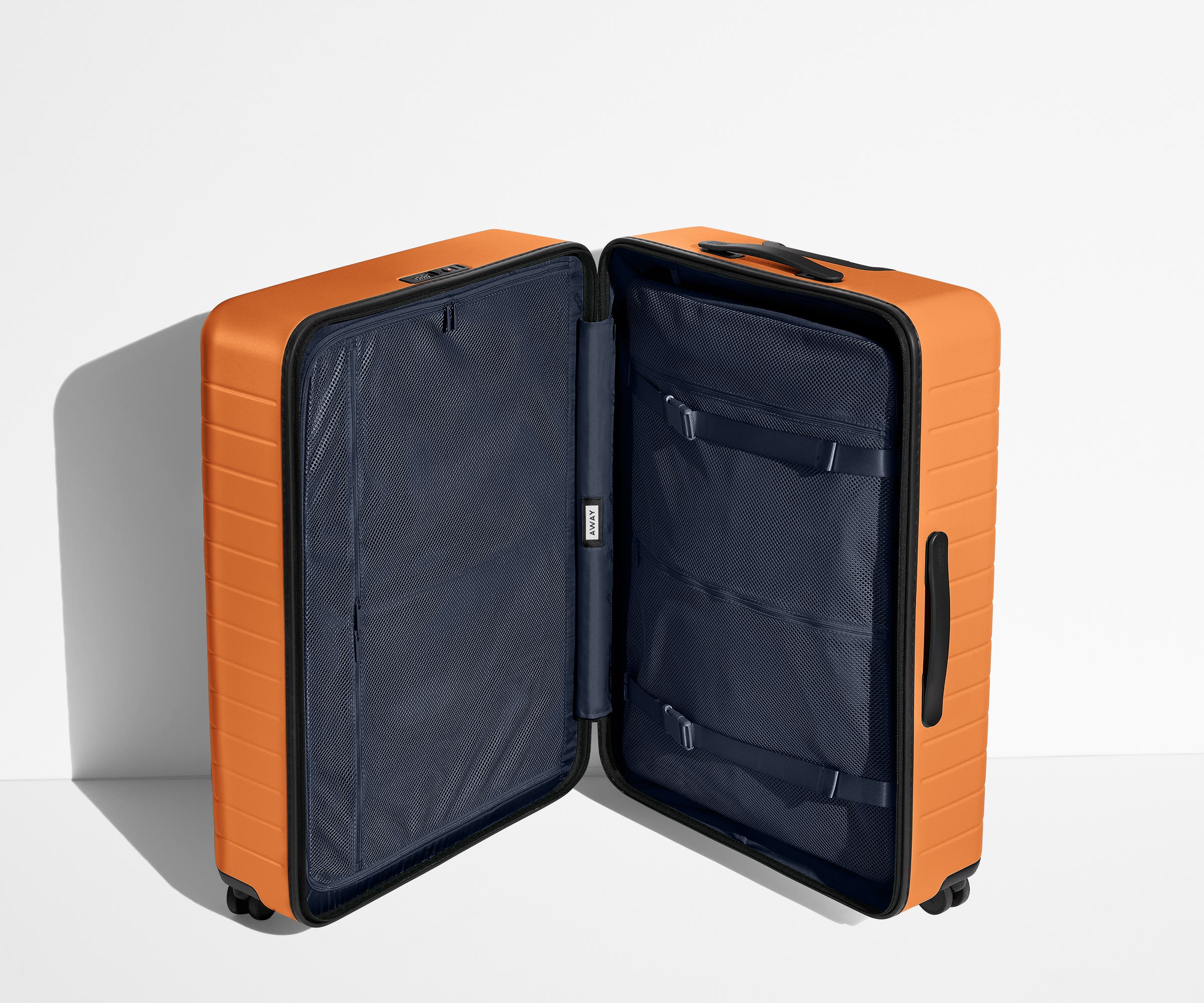 The Large suitcase in Sorbet Orange shown open in an upright position to show interior organization and compression system