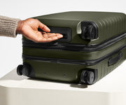 The Bigger Carry-On Flex suitcase in Olive Green shown from below highlighting the underside grab handle