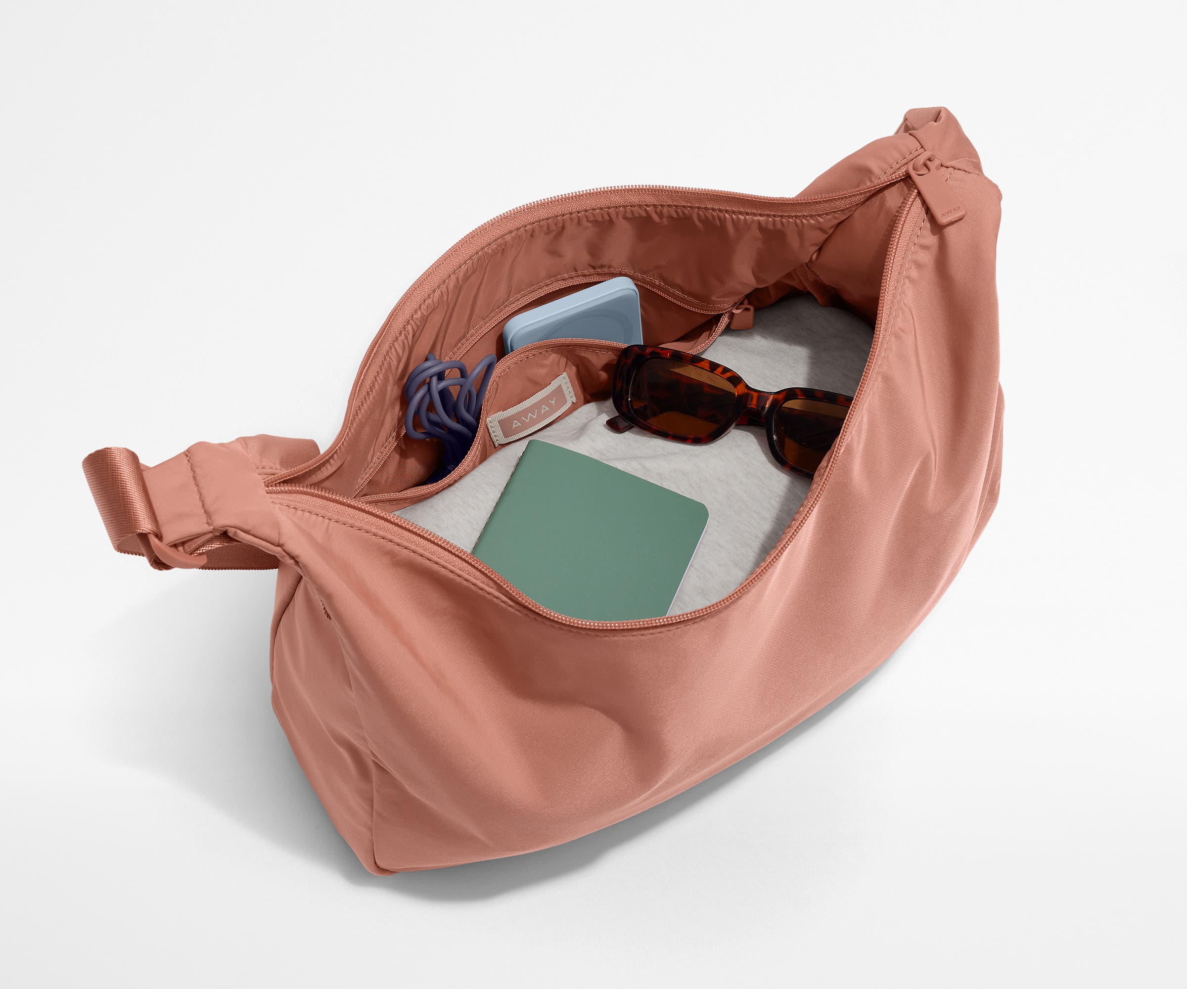 Featherlight crossbody packed with a sweater, notebook, sunglasses, and portable charger