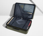 The Large Flex suitcase in Olive Green shown open on its side and packed with Away's packing organizers to show capacity and the interior compression system, designed to help you pack more in