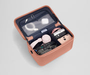 Train case packed with tech gear including multiple cameras, headphones, charging cords, and earpods