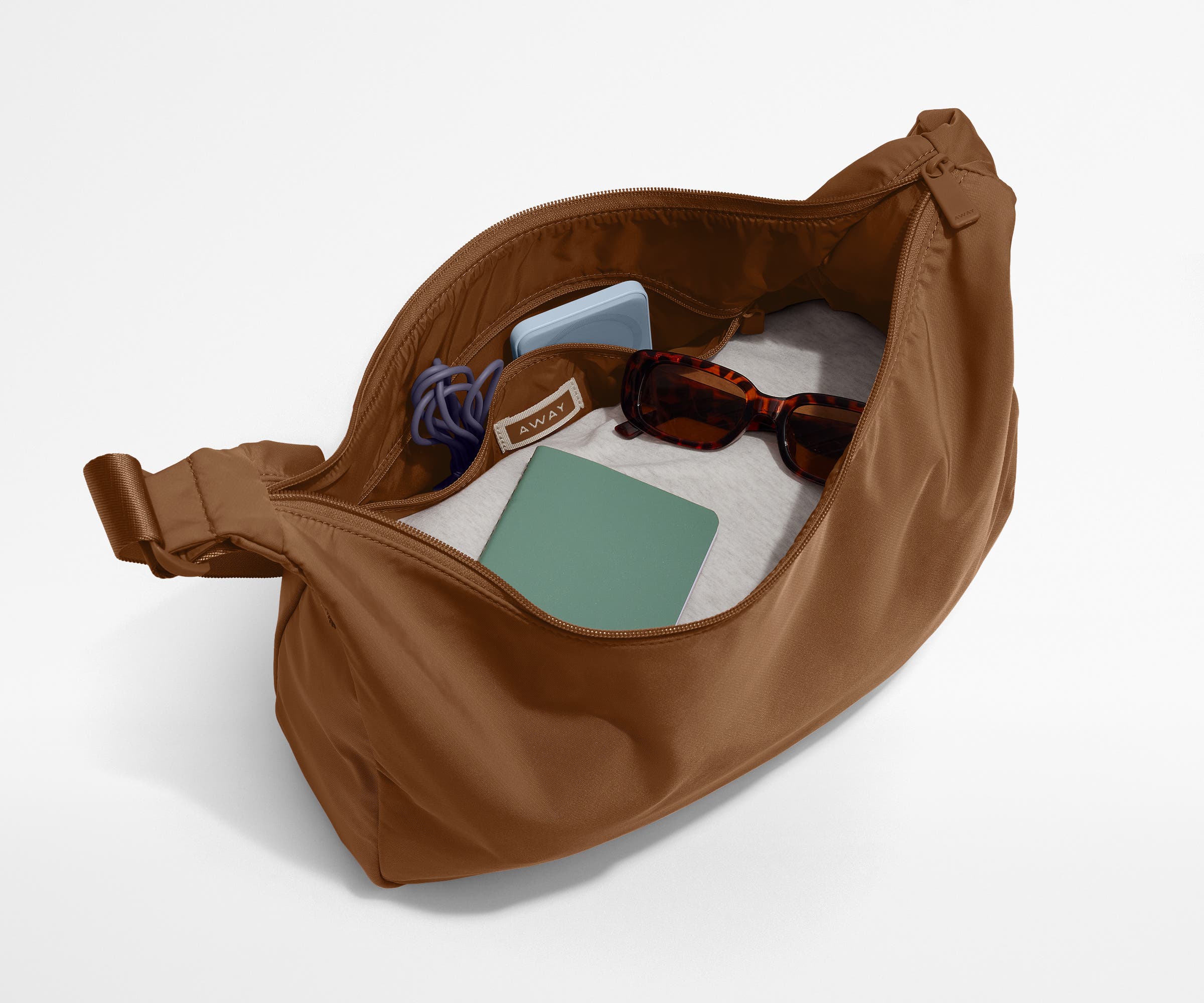 Featherlight crossbody packed with a sweater, notebook, sunglasses, and portable charger