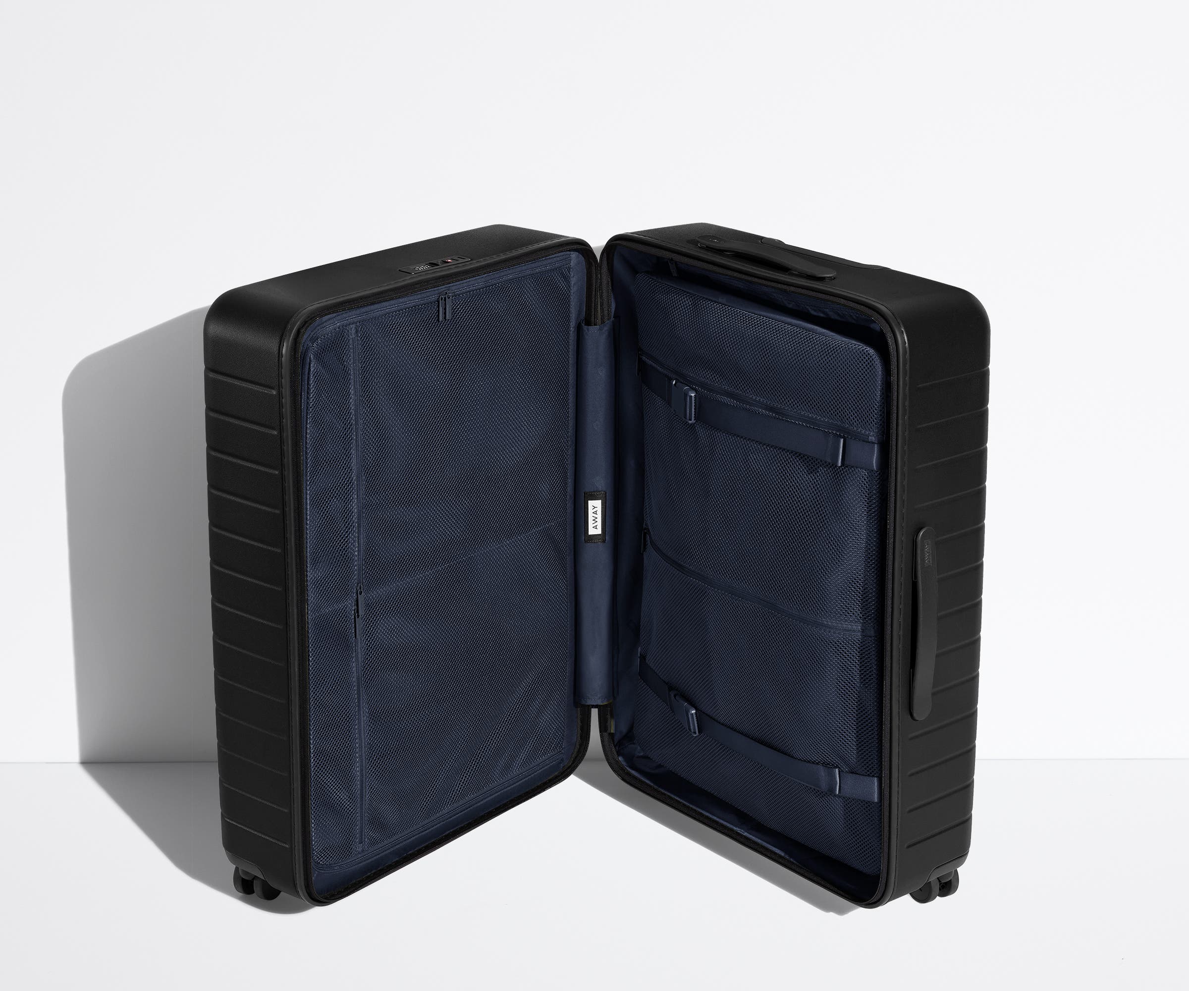 The Large suitcase in Jet Black shown open in an upright position to show interior organization and compression system