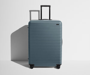 Front product view of The Large suitcase in Coast Blue with raised handle
