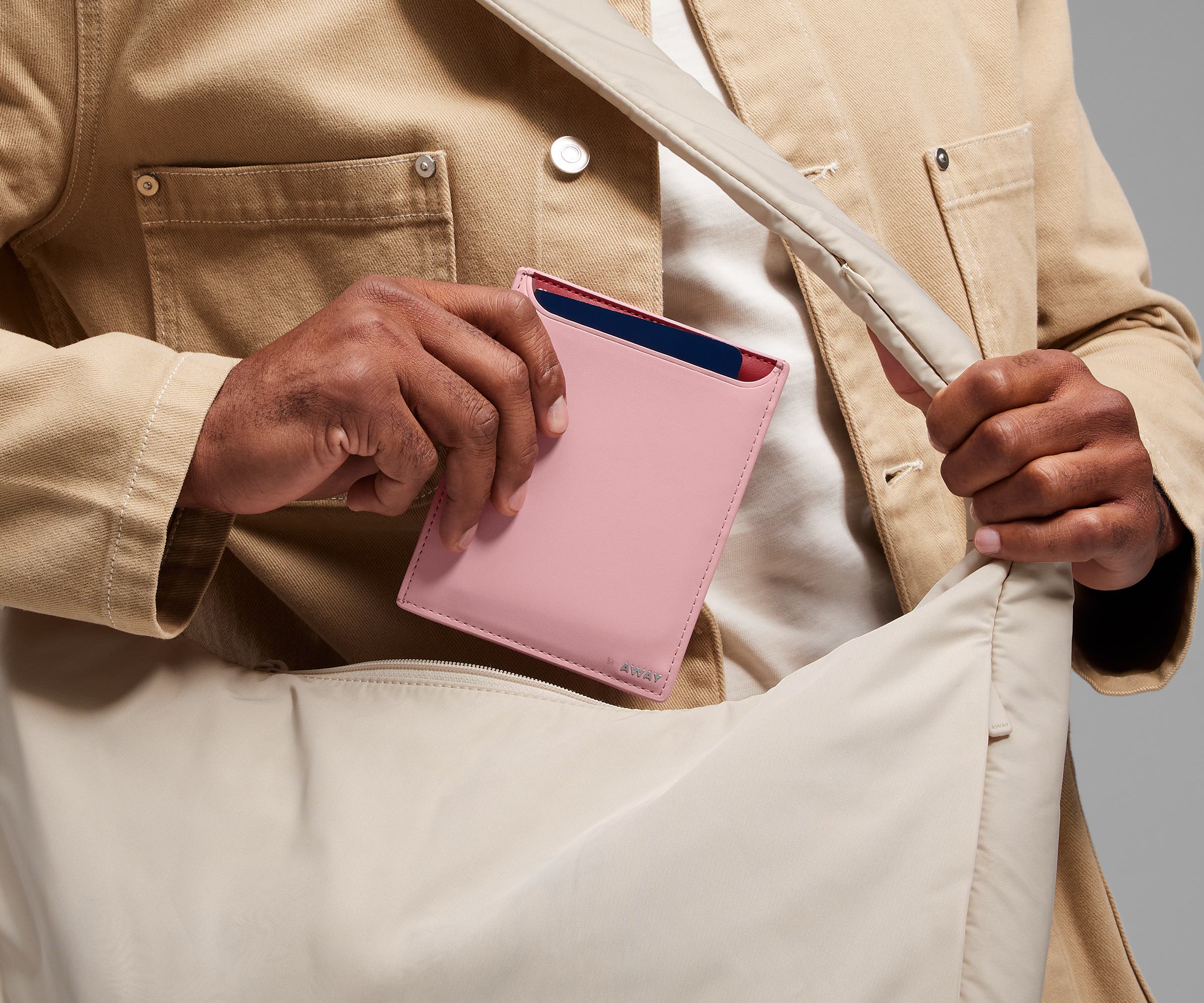 Person packing the Passport Wallet in the Featherlight Crossbody bag