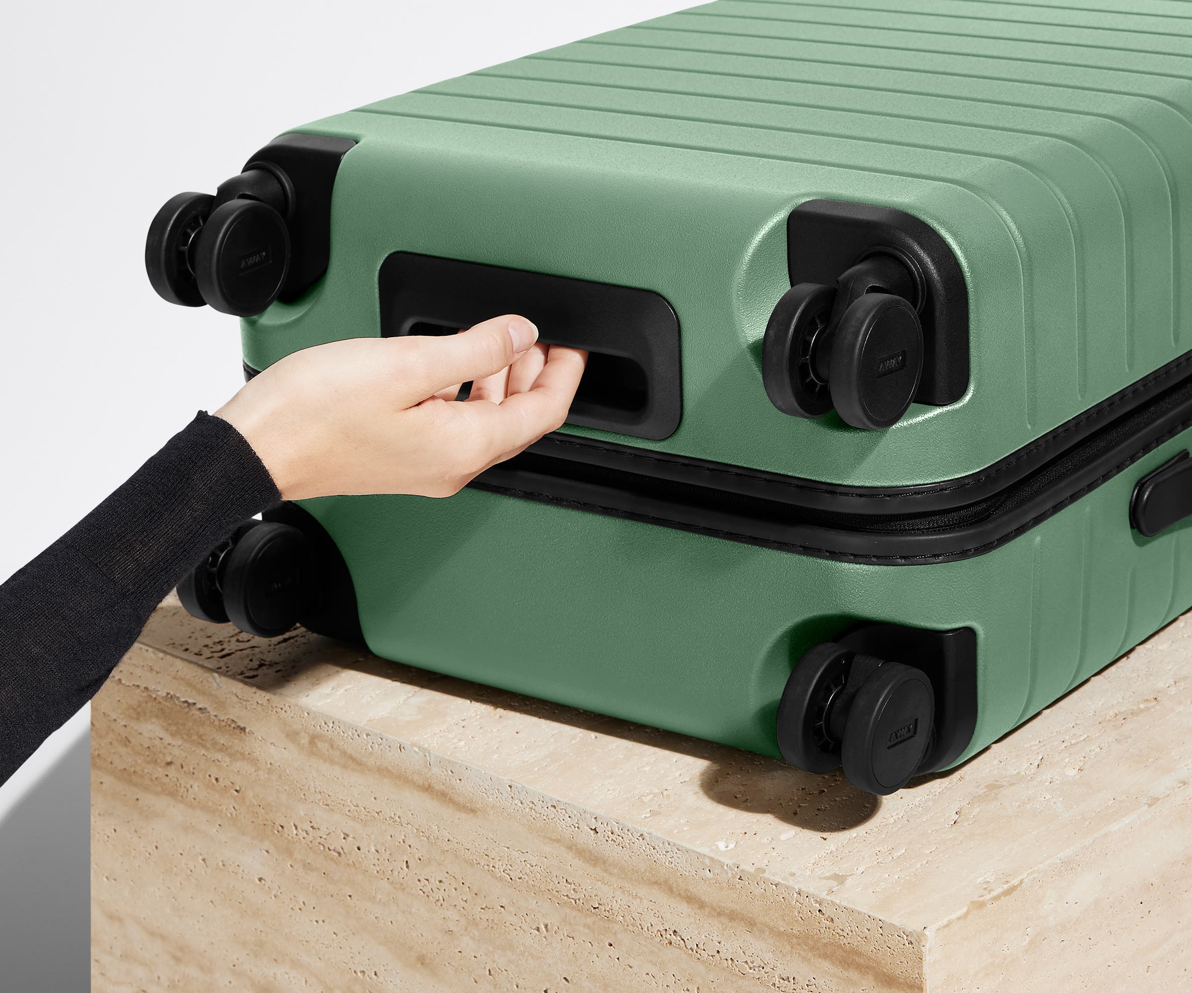 The Carry-On suitcase in Sea Green shown from below highlighting the underside grab handle