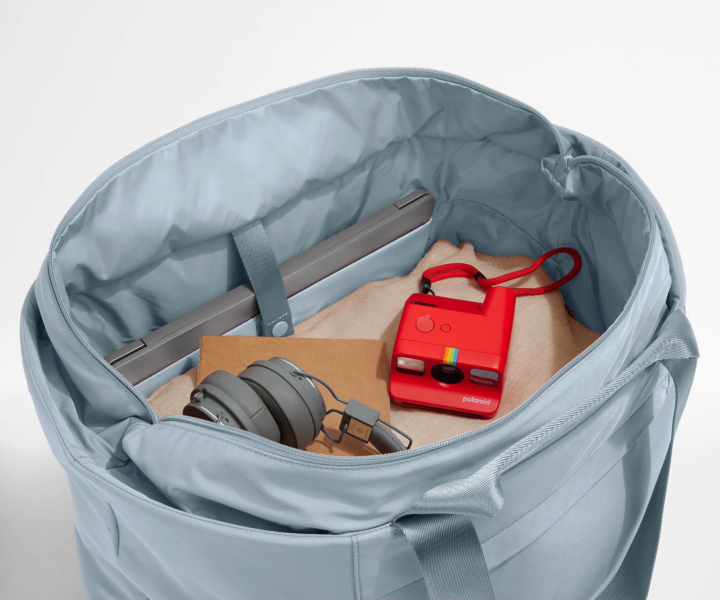 Interior packed with clothing, a laptop, headphones, notebook, and camera