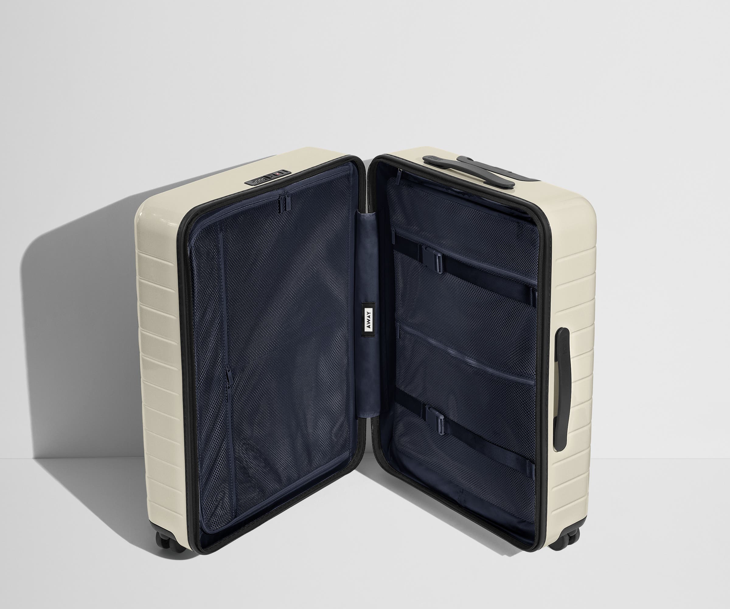 The Medium suitcase in Salt White (Gloss) shown open in an upright position to show interior organization and compression system