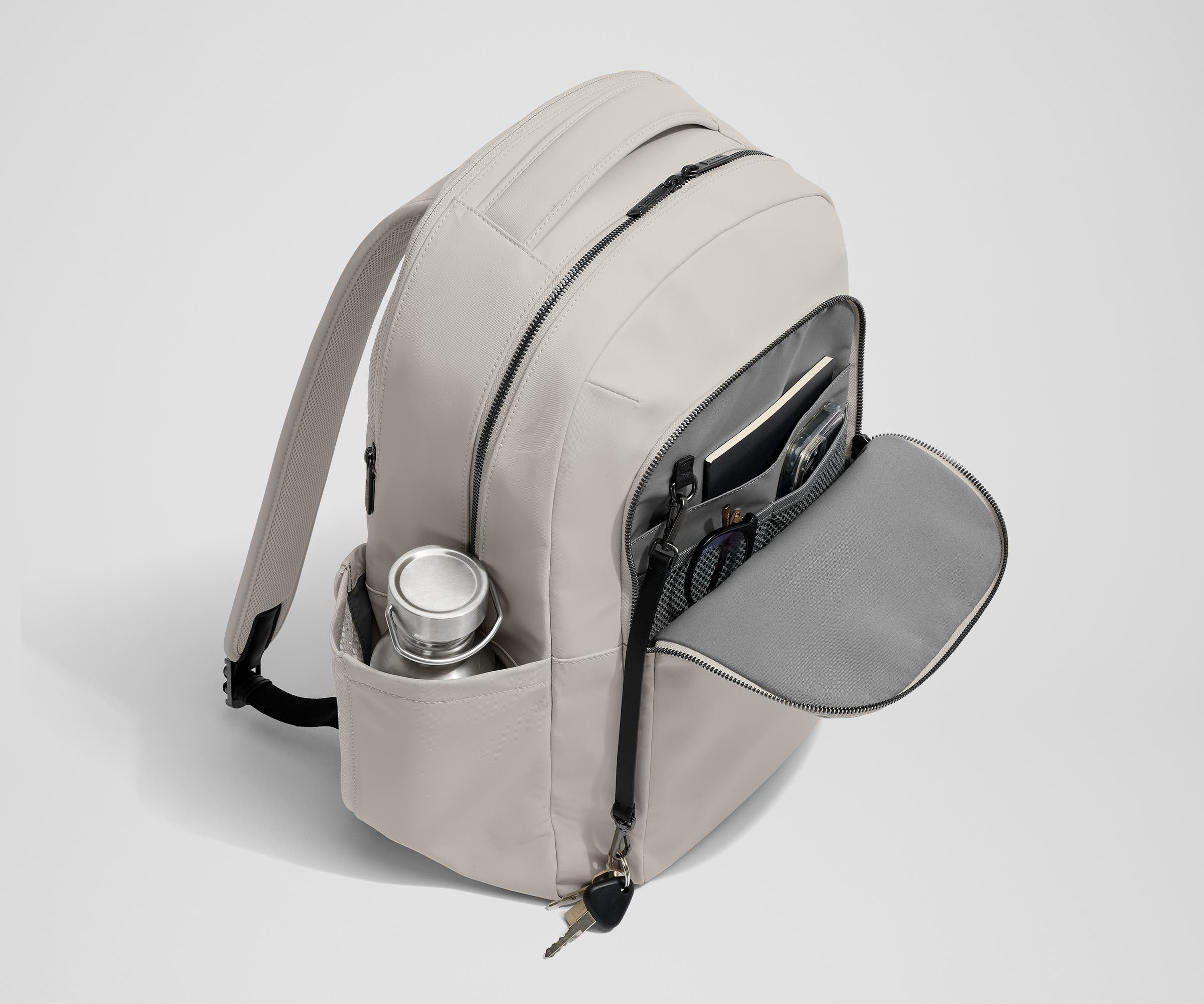 Front exterior zip pocket, detachable key clip, and exterior water bottle pocket of The Commuter Backpack