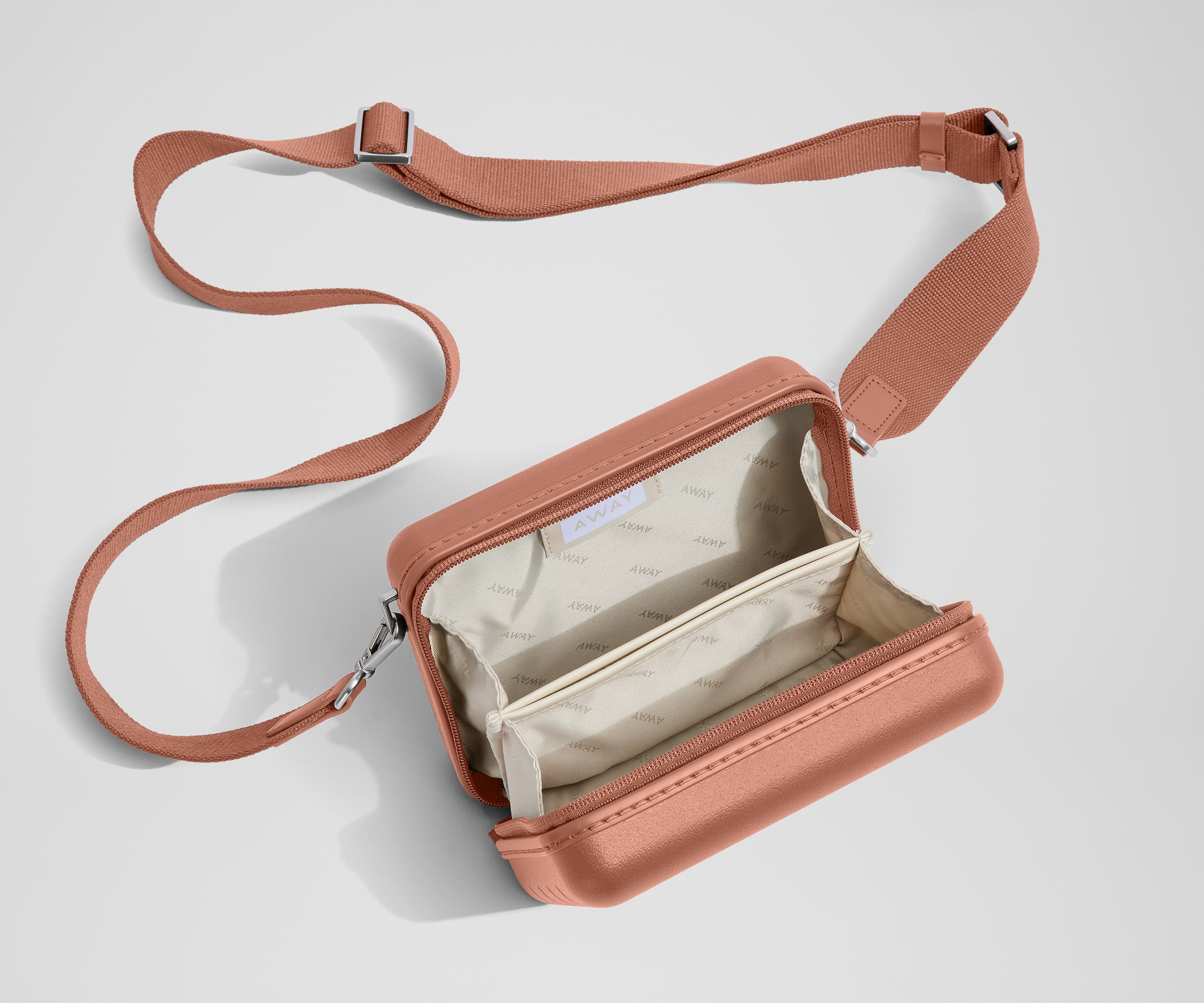 Unzipped, open view of The Mini Crossbody, showing the two main compartments and slip pocket