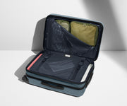 The Carry-On Flex suitcase in Coast Blue shown open on its side and packed with Away's packing organizers to show capacity and the interior compression system, designed to help you pack more in