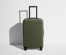 Front product view of The Bigger Carry-On suitcase in Olive Green with raised handle