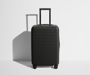 Front product view of The Bigger Carry-On suitcase in Jet Black with raised handle
