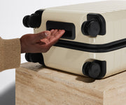 The Bigger Carry-On suitcase in Salt White (Gloss) shown from below highlighting the underside grab handle