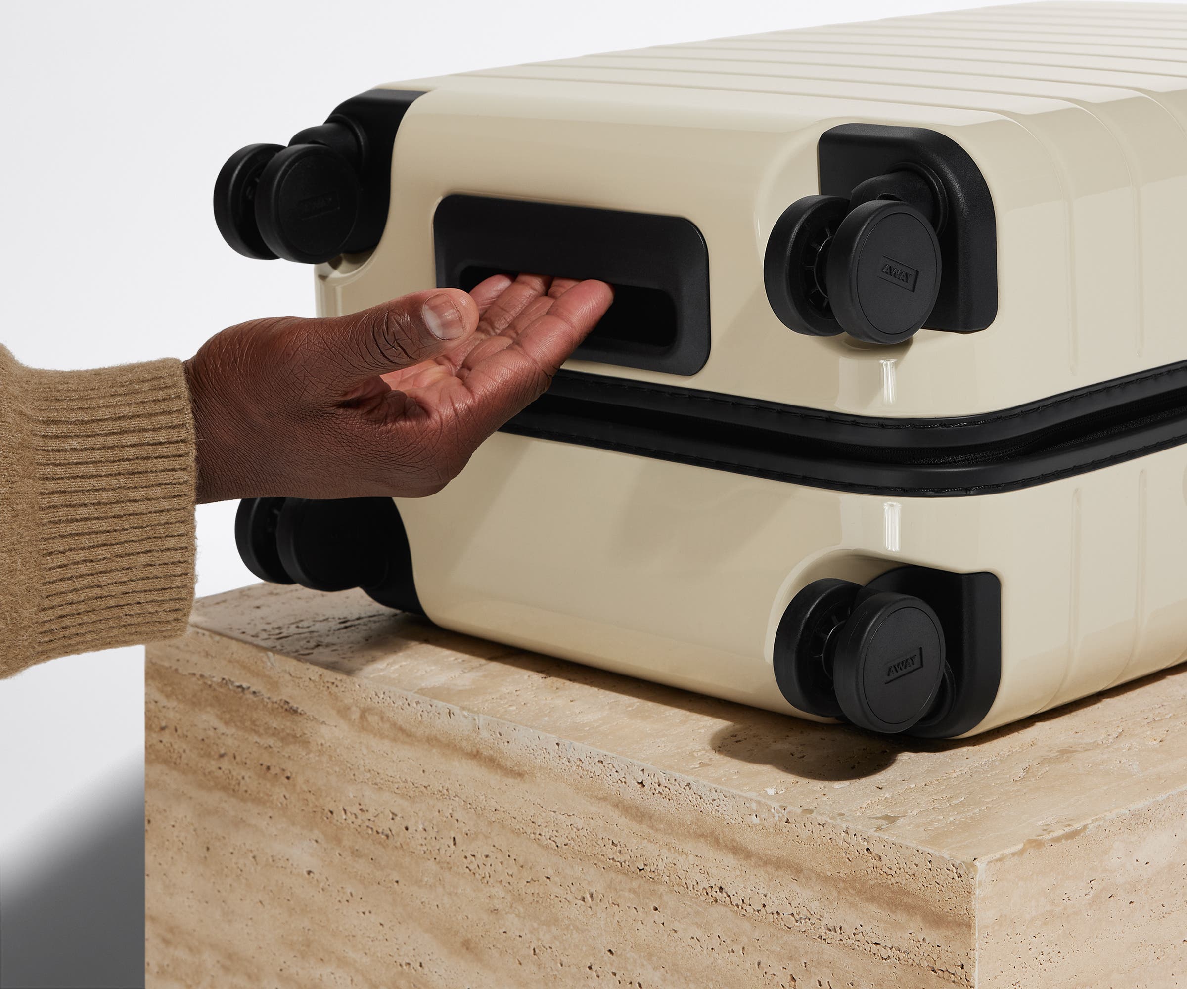 The Bigger Carry-On suitcase in Salt White (Gloss) shown from below highlighting the underside grab handle