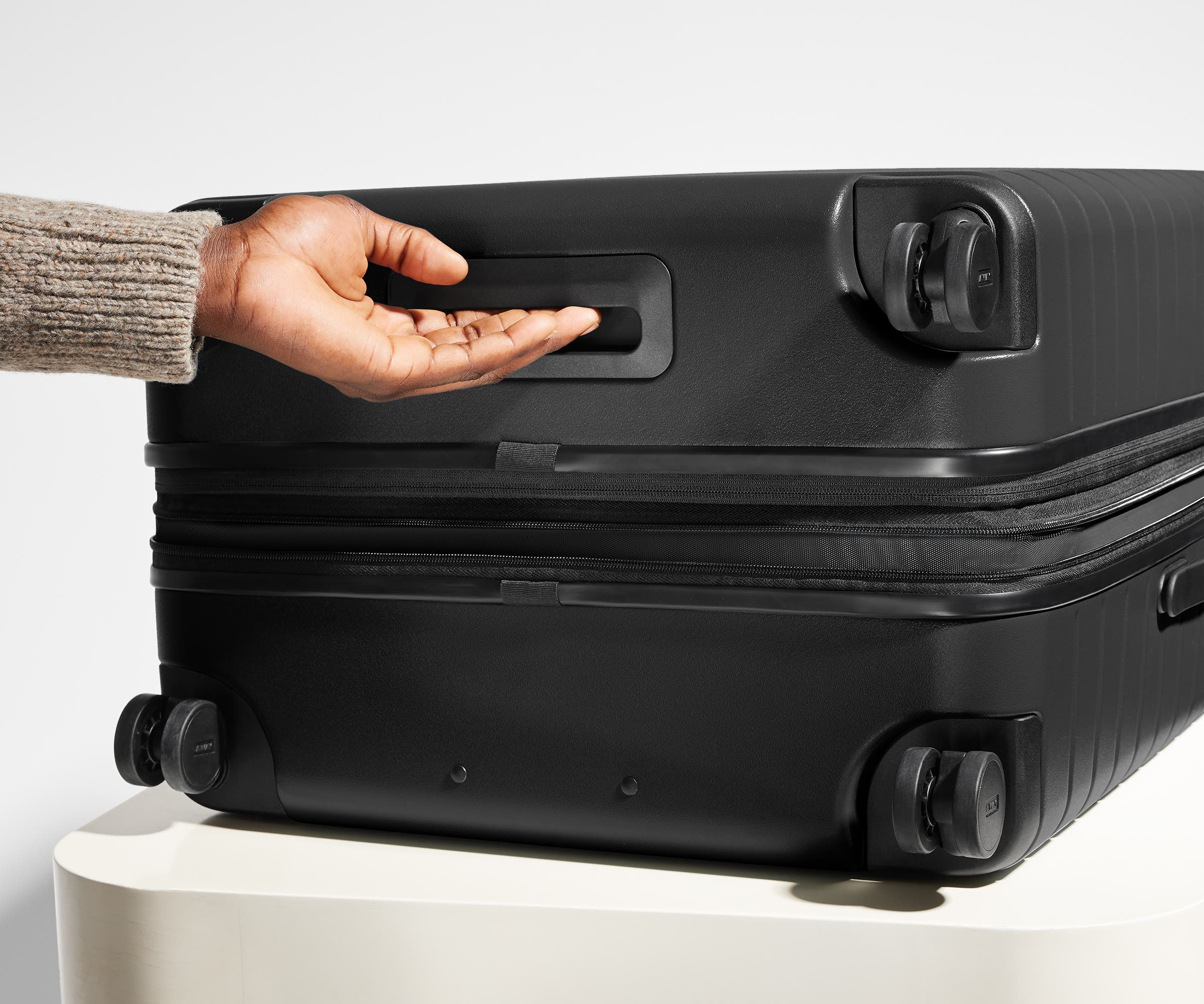 The Large Flex suitcase in Jet Black shown from below highlighting the underside grab handle