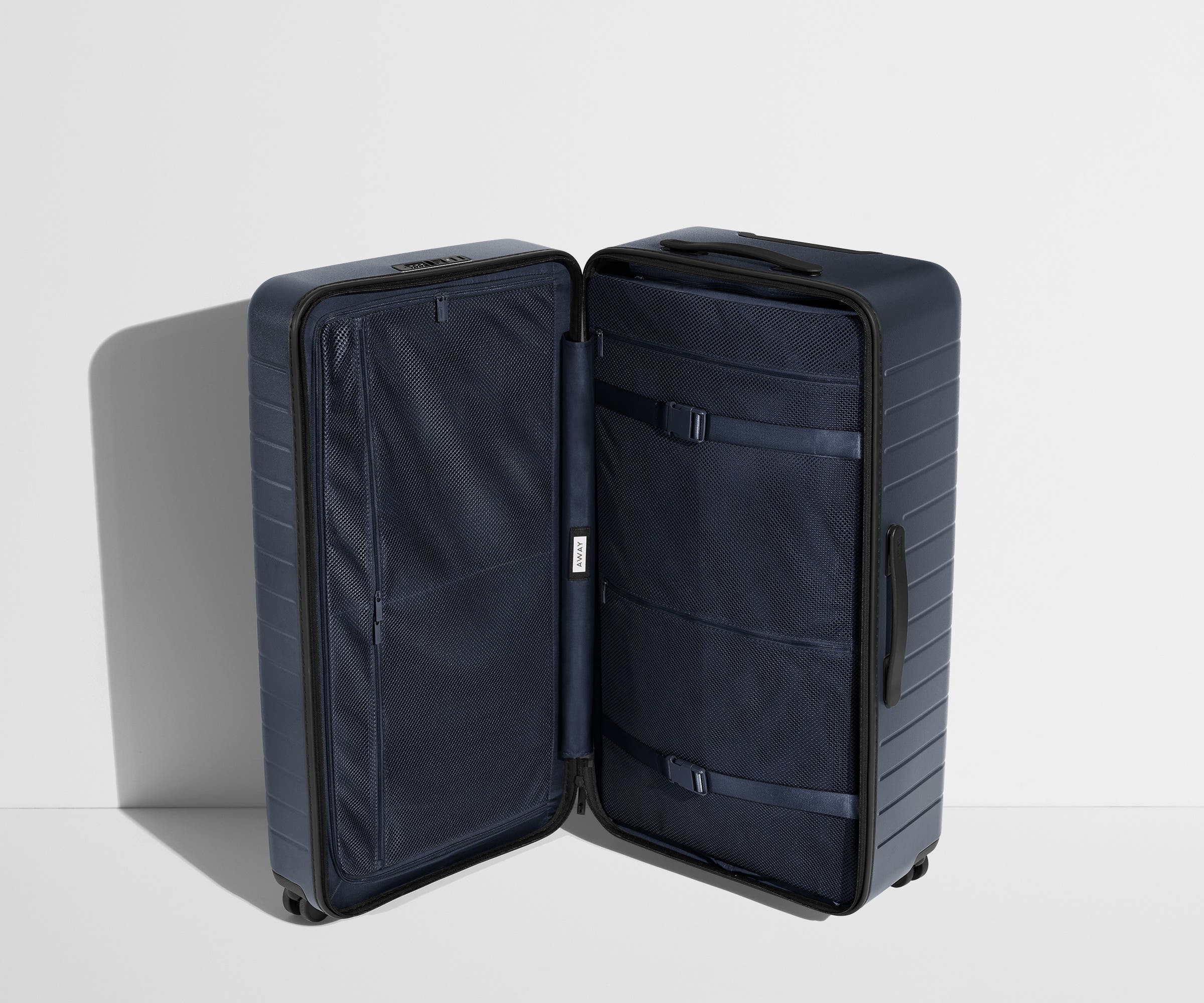 The Trunk suitcase in Navy Blue shown open in an upright position to show interior organization and compression system