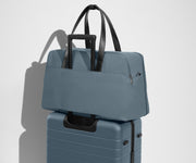Weekender sitting on an Away Large suitcase, using the trolley sleeve pass-through