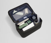 Train case packed with multiple grooming essentials, including a razor, nail care, and lotions