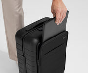 Zoomed in shot of talent slipping a laptop into the front pocket of The Front Pocket Carry-On in Jet Black