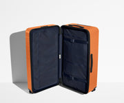 The Trunk suitcase in Sorbet Orange shown open in an upright position to show interior organization and compression system