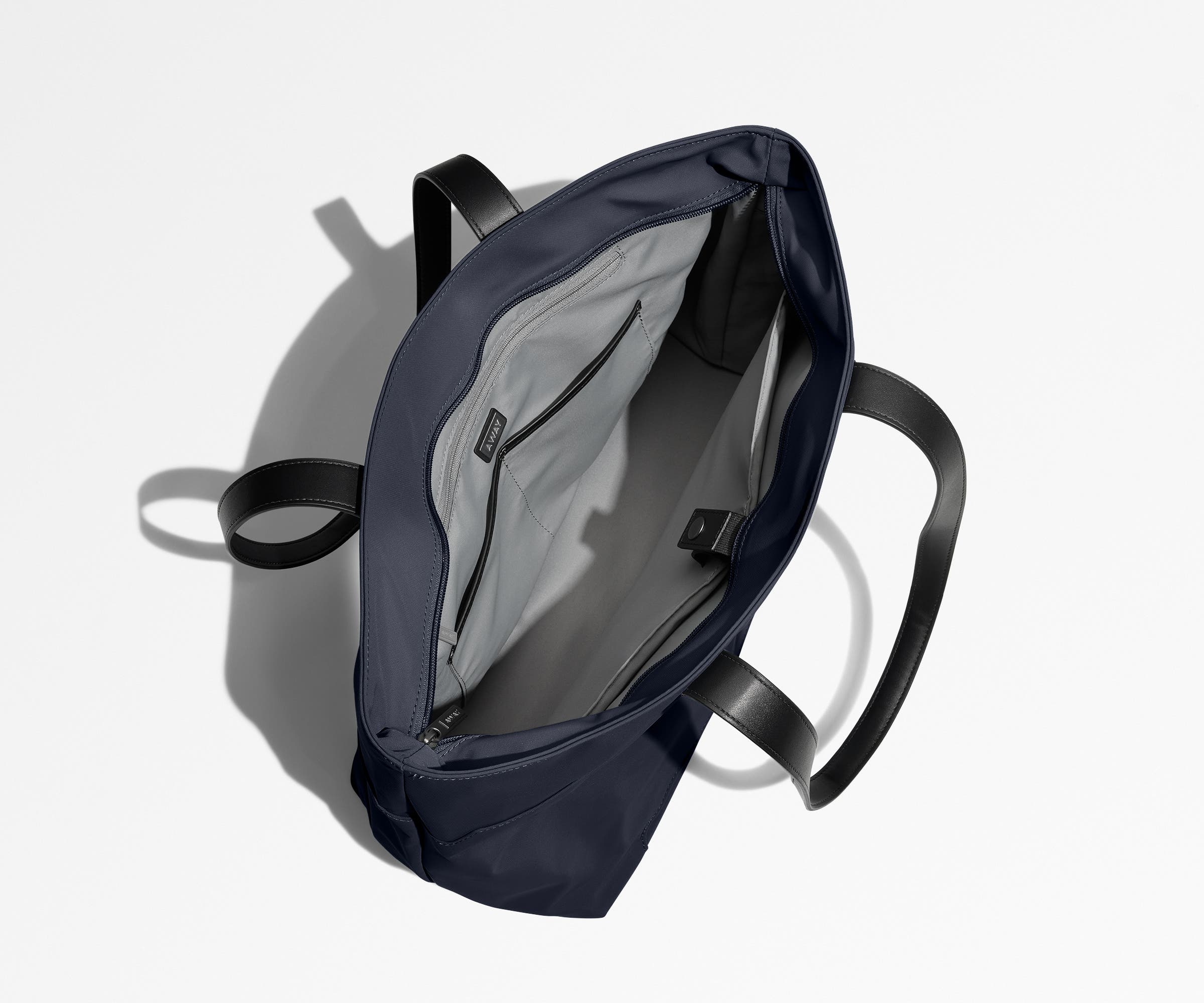 Unzipped and unpacked Everywhere Tote bag, showing the interior zip pockets, slip pockets, and laptop pocket