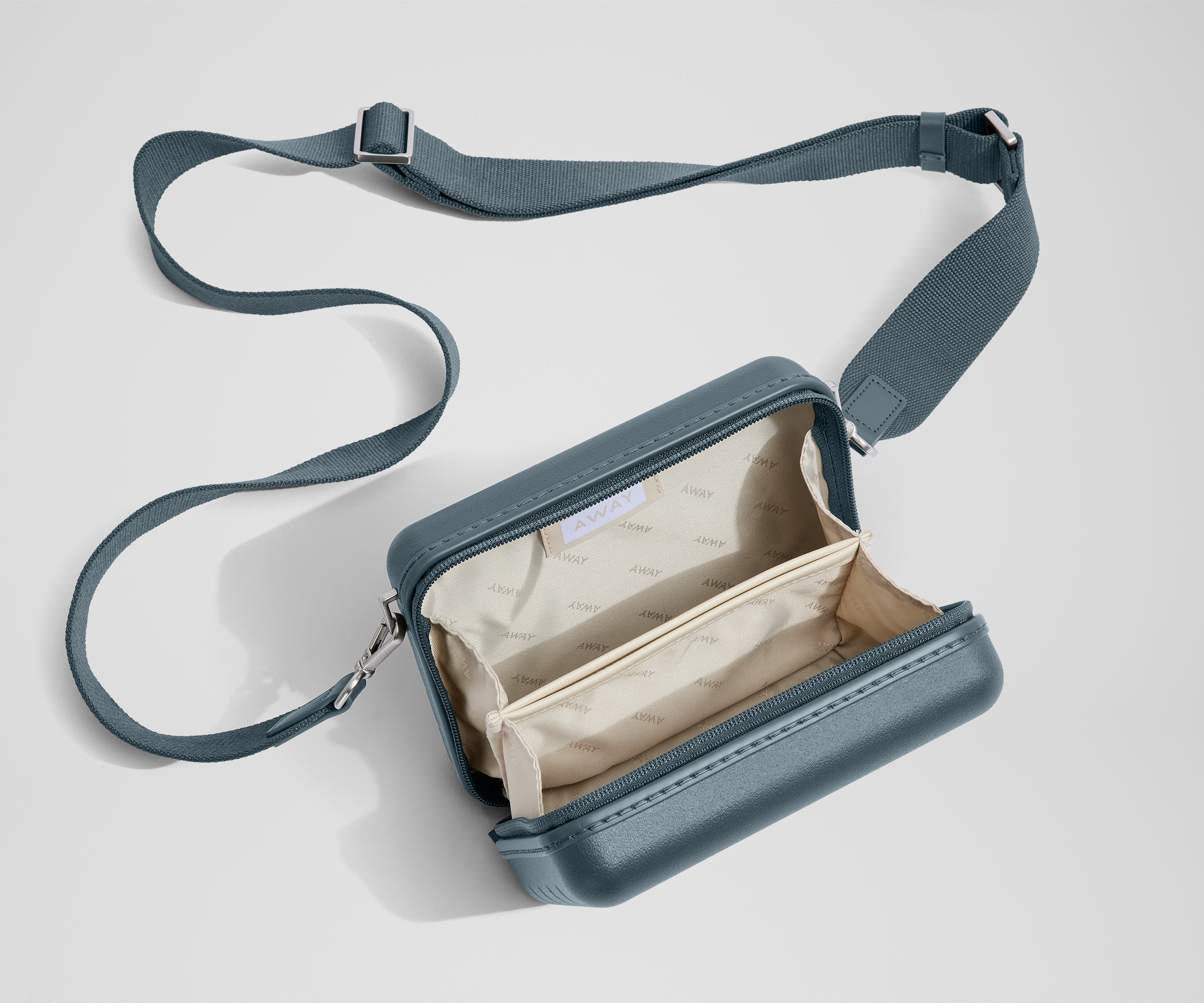 Unzipped, open view of The Mini Crossbody, showing the two main compartments and slip pocket