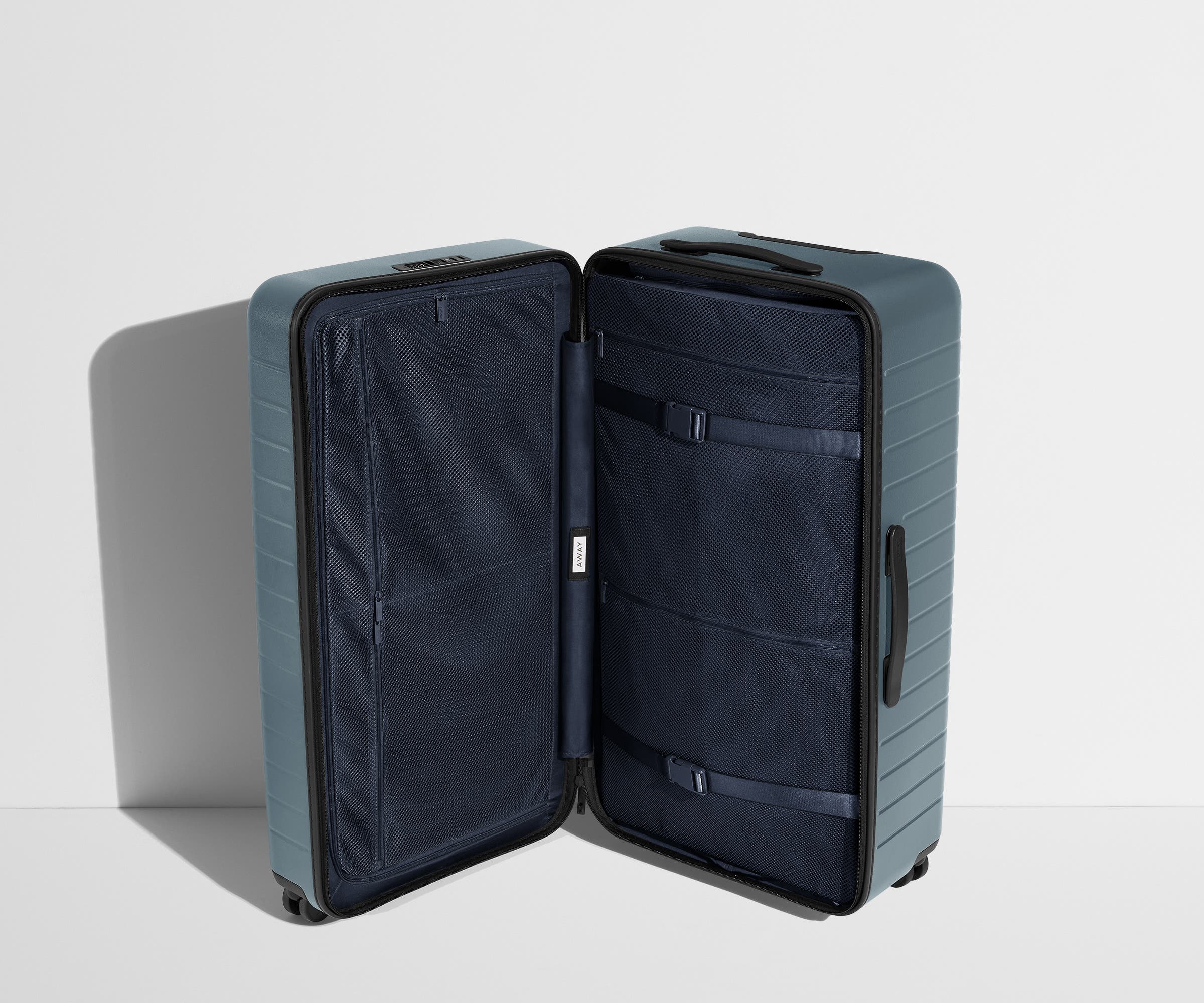The Trunk suitcase in Coast Blue shown open in an upright position to show interior organization and compression system