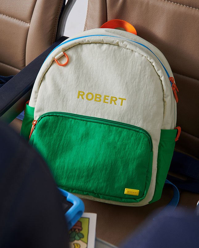 A green Away duffle with three letters embroidered on the back