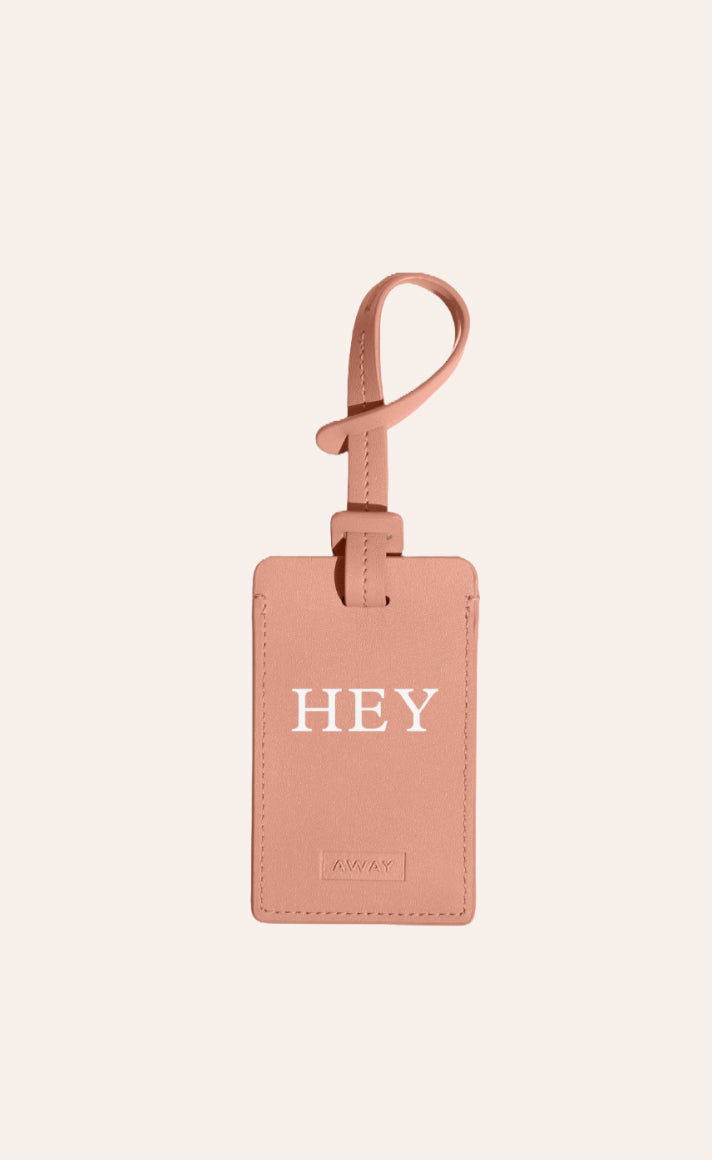A green Away luggage tag with initials foil stamped on it