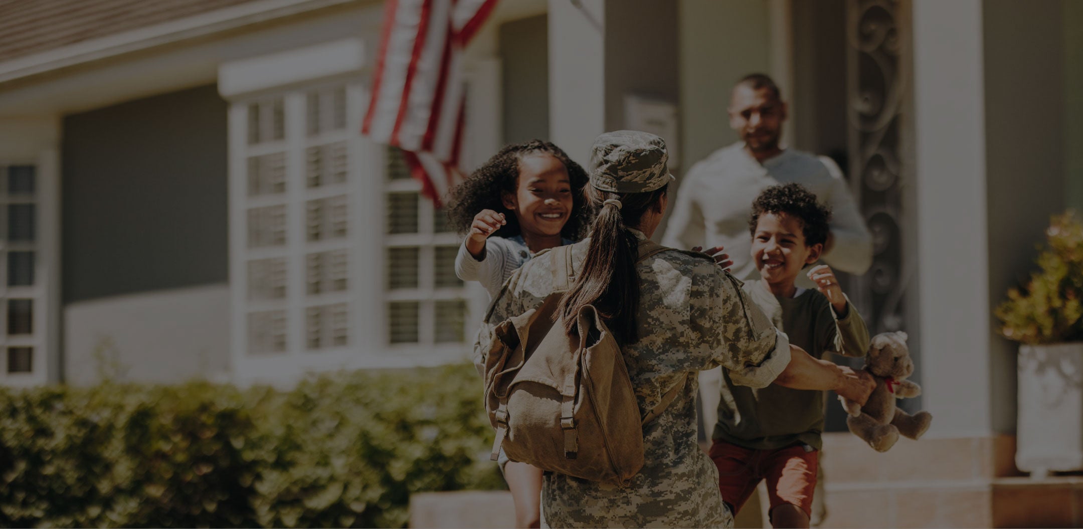 American soldier returning home hugging her family outside their home.