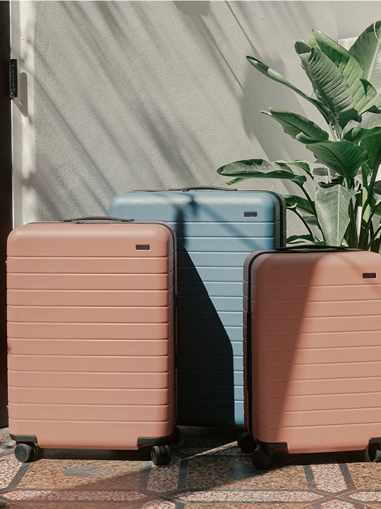Front product view of a Carry-On and checked suitcase in Clay Pink and a Large suitcase in Coast Blue