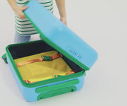 A child model filling The Kids Carry-On suitcase in Splash Blue with Away's packing organizers and using the interior organization and compression system for seamless packing