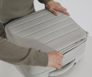 A female model filling The Softside Compact Carry-On suitcase with Away's packing organizers and using the interior organization and compression system for seamless packing